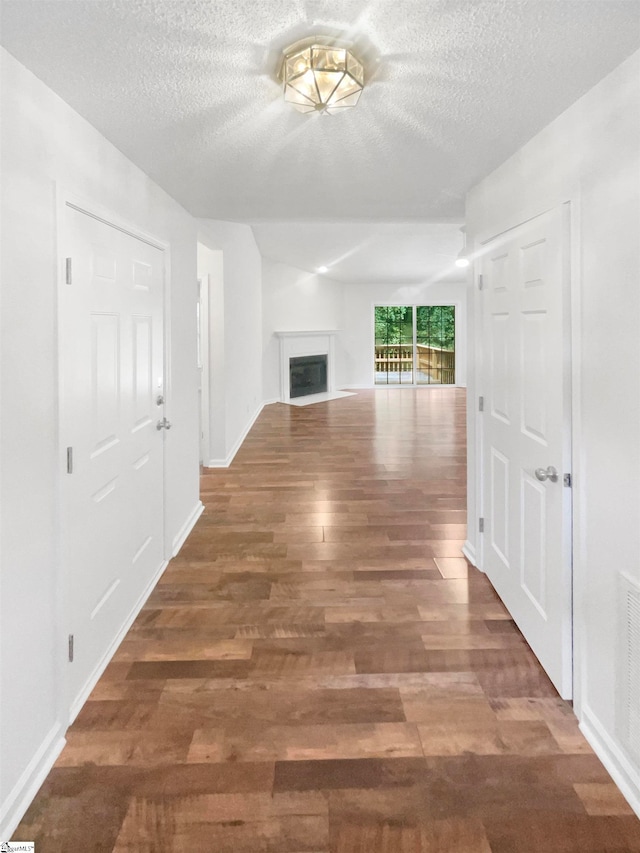 hall with a textured ceiling and dark hardwood / wood-style floors