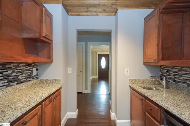 kitchen featuring dark wood-type flooring, sink, light stone countertops, and decorative backsplash