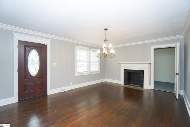 foyer featuring ornamental molding, a notable chandelier, dark hardwood / wood-style flooring, and a fireplace