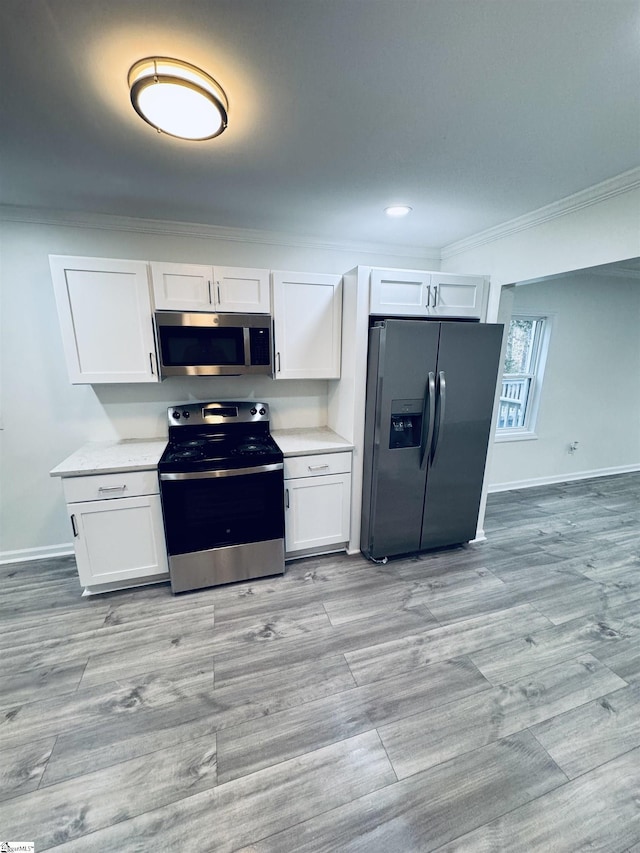 kitchen featuring stainless steel appliances, white cabinetry, and crown molding