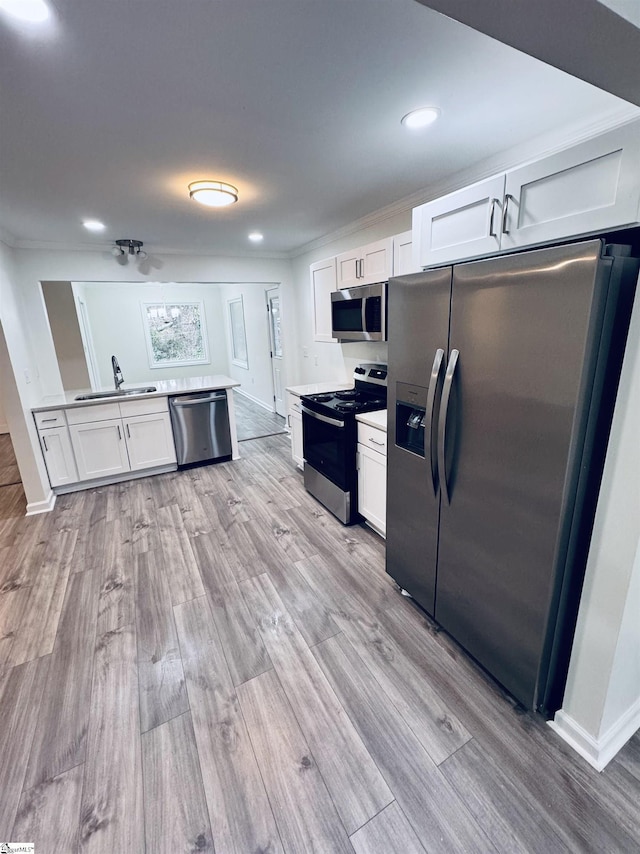 kitchen featuring white cabinetry, sink, appliances with stainless steel finishes, and light hardwood / wood-style flooring