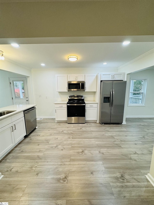 kitchen featuring white cabinetry, crown molding, stainless steel appliances, and light hardwood / wood-style floors