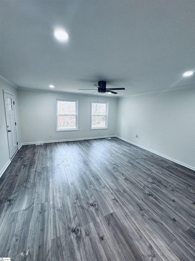 empty room featuring ceiling fan, crown molding, and dark wood-type flooring