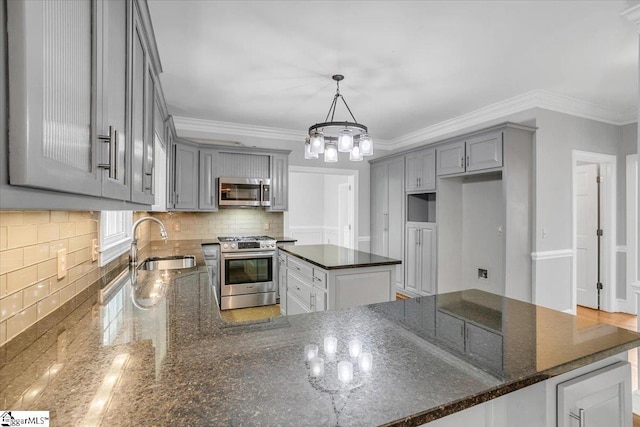 kitchen featuring stainless steel appliances, a chandelier, sink, kitchen peninsula, and pendant lighting