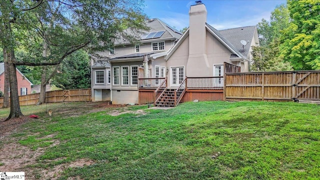 back of property with a wooden deck and a yard