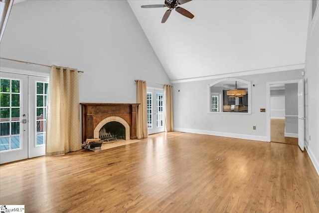 unfurnished living room featuring a healthy amount of sunlight, ceiling fan, high vaulted ceiling, and light hardwood / wood-style floors