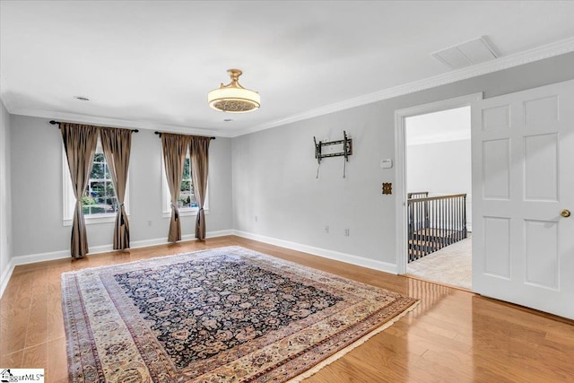 spare room with ornamental molding and light hardwood / wood-style flooring