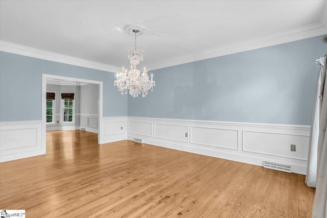 unfurnished dining area featuring crown molding, a chandelier, and hardwood / wood-style floors