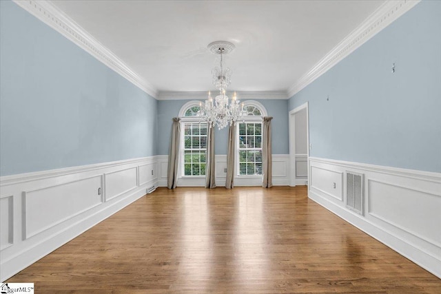 unfurnished dining area with crown molding, wood-type flooring, and a notable chandelier