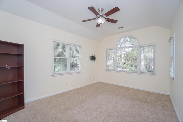 spare room featuring vaulted ceiling, light colored carpet, and plenty of natural light