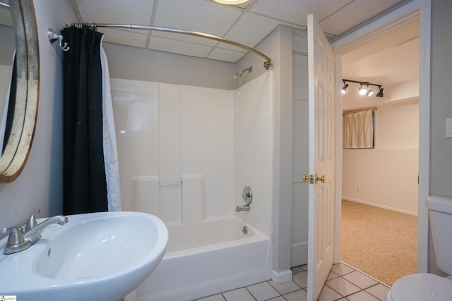 full bathroom featuring shower / bathtub combination with curtain, sink, a paneled ceiling, tile patterned floors, and toilet