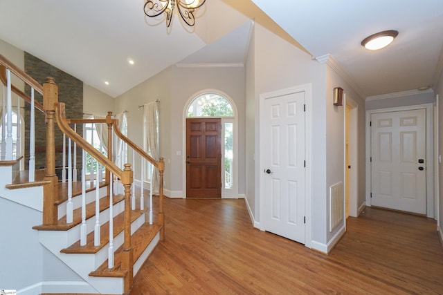 foyer entrance featuring hardwood / wood-style flooring, ornamental molding, and vaulted ceiling