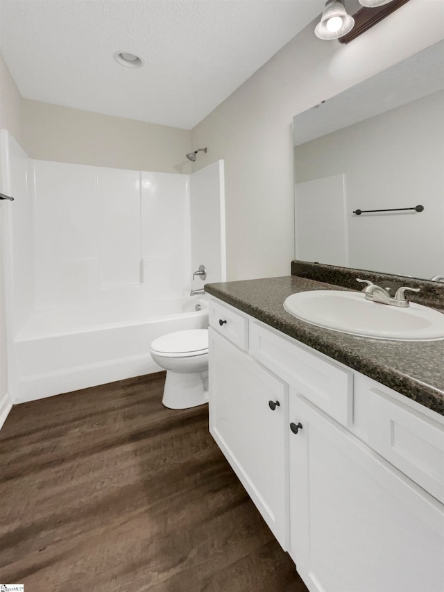 full bathroom with toilet, vanity, a textured ceiling, bathtub / shower combination, and wood-type flooring