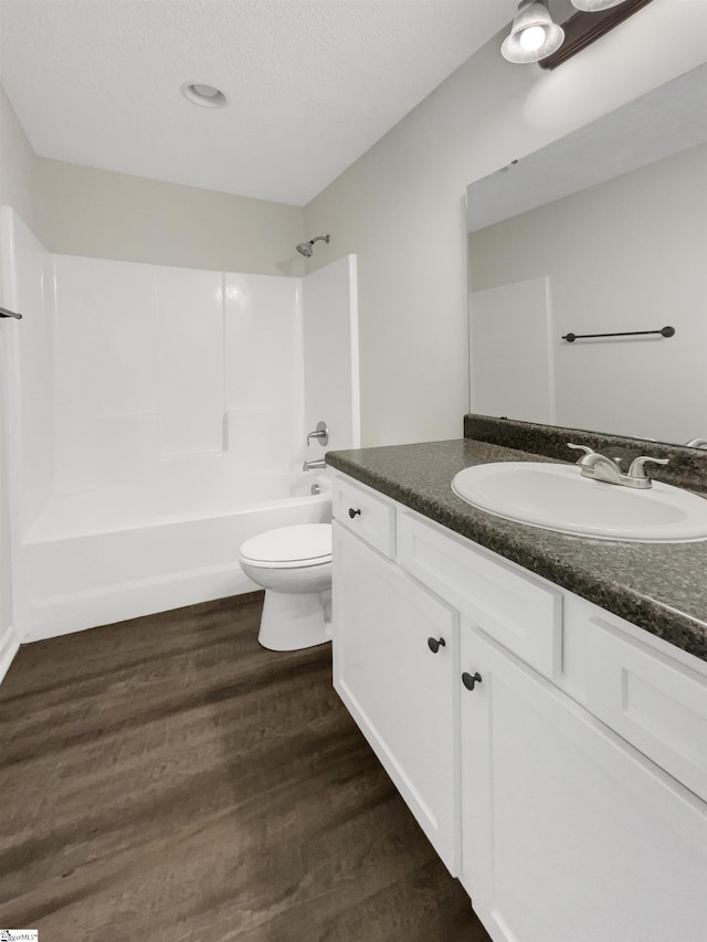 bathroom with vanity, toilet, wood finished floors, and bathtub / shower combination