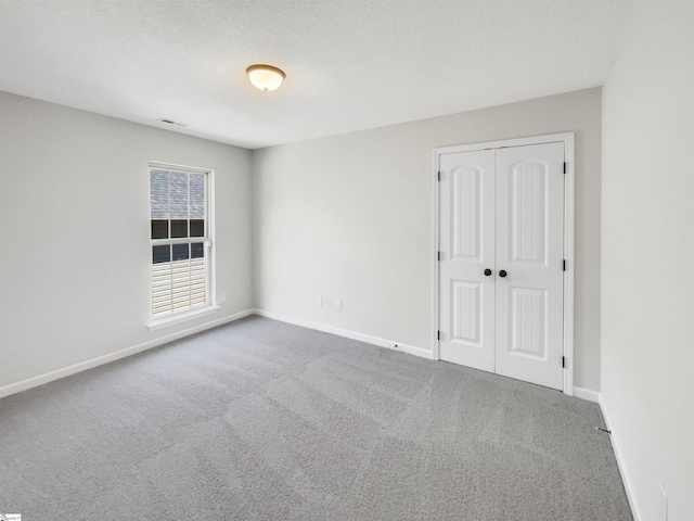 carpeted empty room featuring visible vents, baseboards, and a textured ceiling