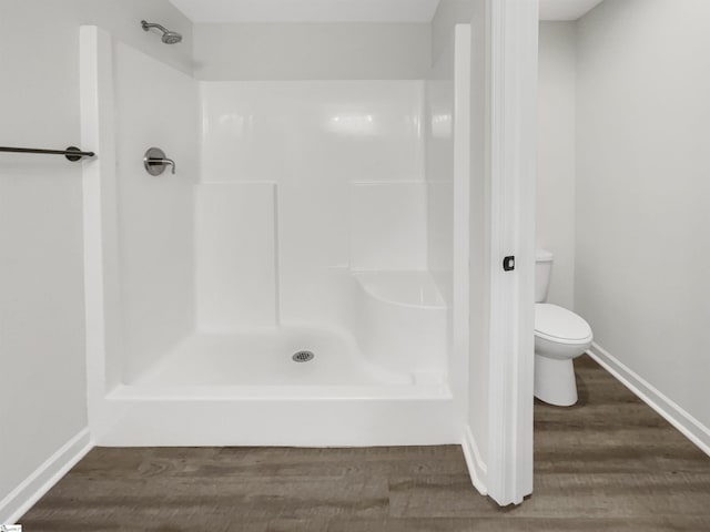 full bath with toilet, wood finished floors, baseboards, and walk in shower