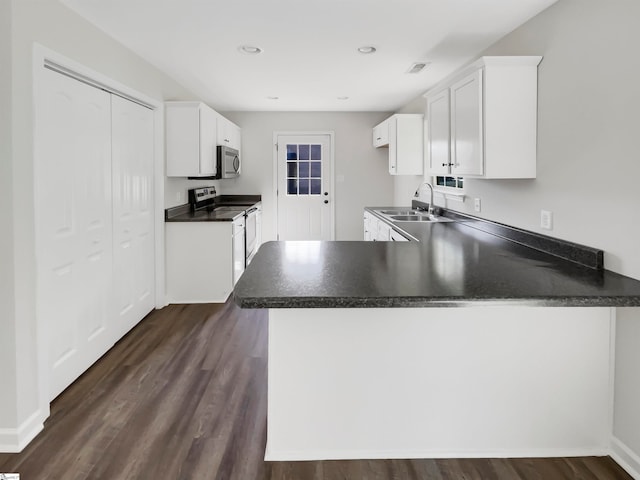 kitchen with stainless steel appliances, dark hardwood / wood-style floors, kitchen peninsula, and white cabinetry