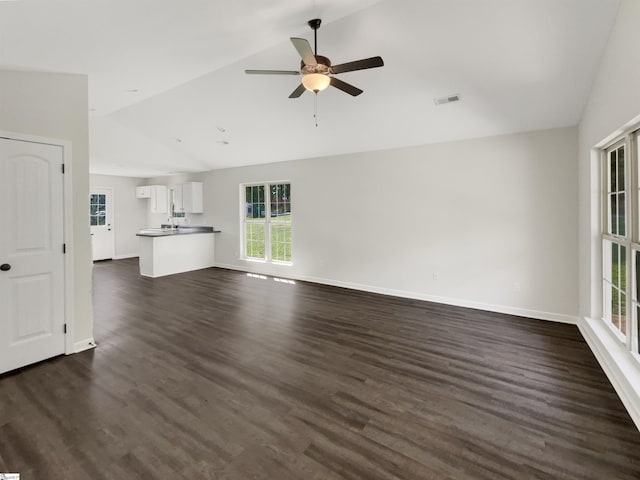 unfurnished living room featuring a ceiling fan, dark wood-style floors, visible vents, baseboards, and vaulted ceiling