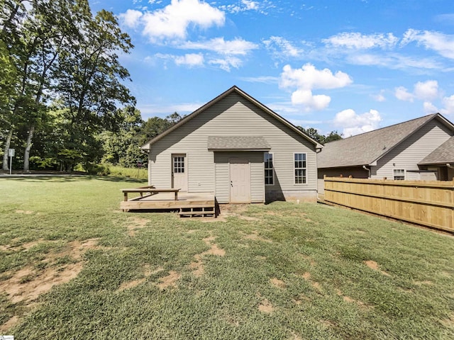 rear view of house featuring a lawn, a wooden deck, and fence