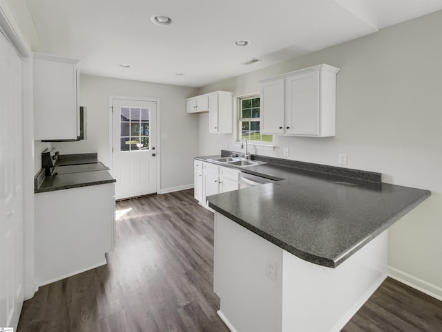 kitchen featuring a peninsula, a sink, stove, white cabinets, and dark countertops