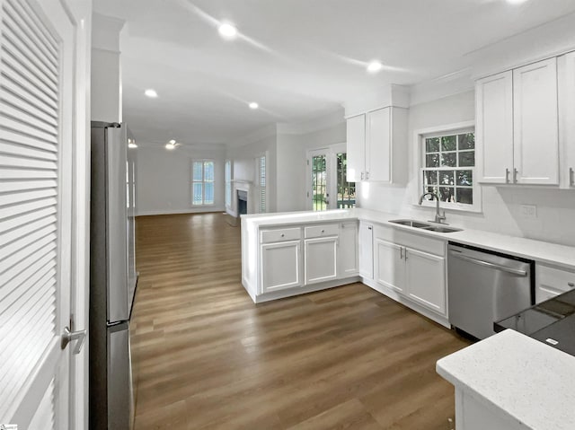 kitchen with a fireplace, wood finished floors, white cabinets, stainless steel appliances, and a sink