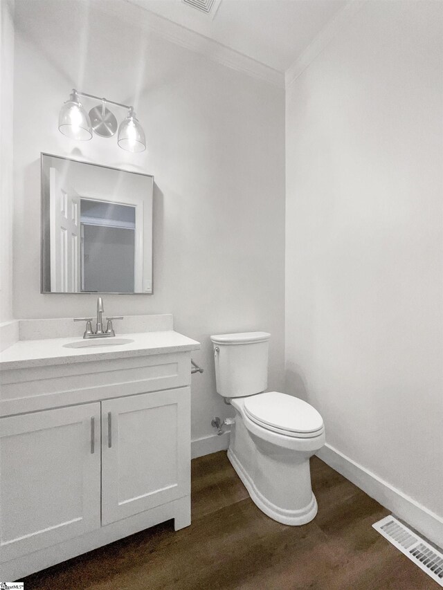 bathroom with vanity, toilet, ornamental molding, and hardwood / wood-style flooring