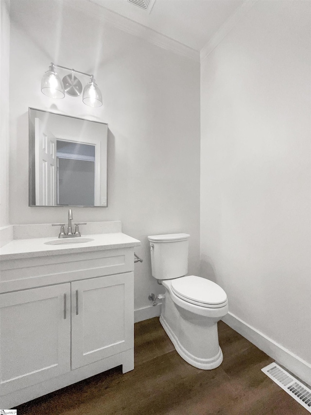 bathroom with visible vents, toilet, ornamental molding, wood finished floors, and vanity