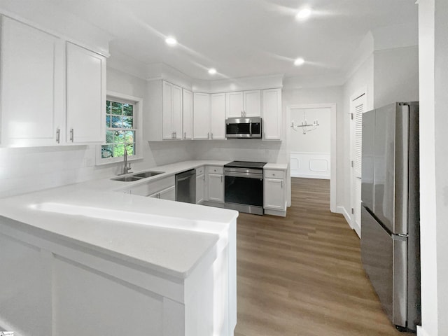 kitchen featuring appliances with stainless steel finishes, kitchen peninsula, sink, white cabinetry, and light wood-type flooring