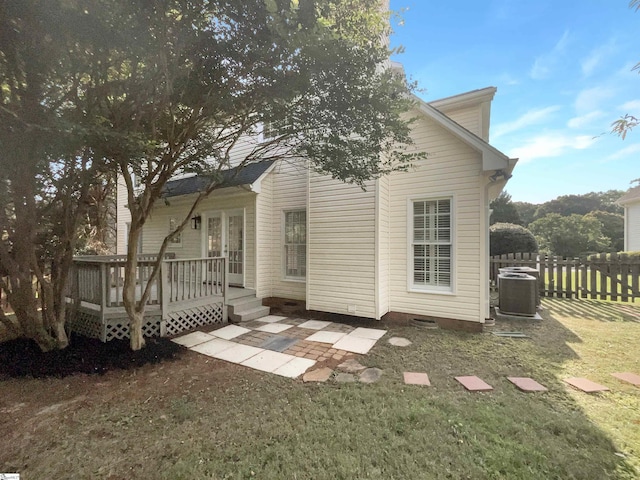 rear view of property with a wooden deck, a yard, central AC unit, and fence