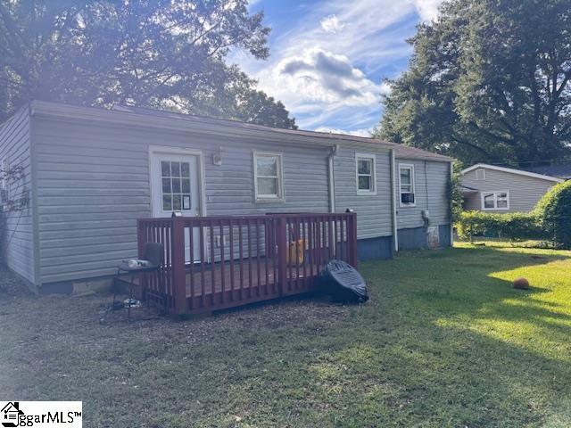 back of house featuring a wooden deck and a yard