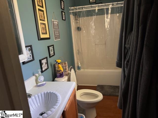 full bathroom featuring wood-type flooring, vanity, shower / bath combo with shower curtain, and toilet