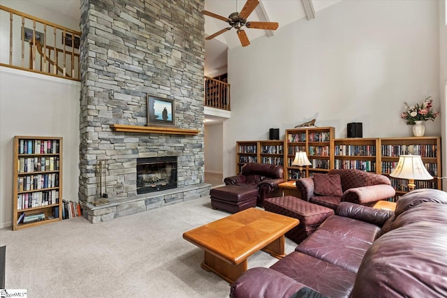 carpeted living room with high vaulted ceiling, beam ceiling, ceiling fan, and a stone fireplace