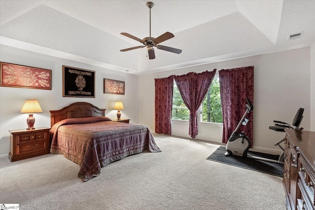 bedroom with a tray ceiling, light colored carpet, and ceiling fan