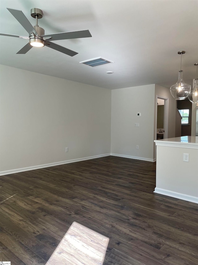 unfurnished room with ceiling fan with notable chandelier and dark hardwood / wood-style floors