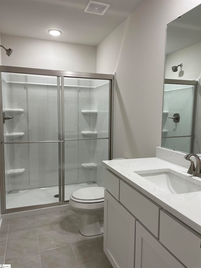 bathroom featuring vanity, toilet, tile patterned flooring, and a shower with door