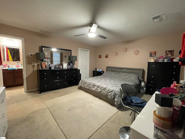 carpeted bedroom featuring a closet, ceiling fan, and ensuite bath