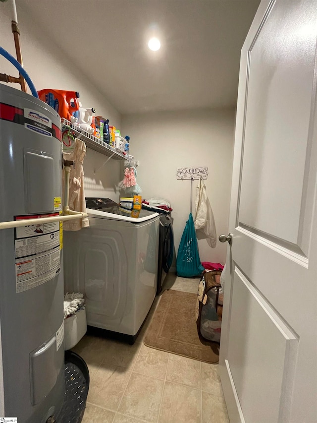 clothes washing area featuring water heater, light tile patterned floors, and washing machine and clothes dryer