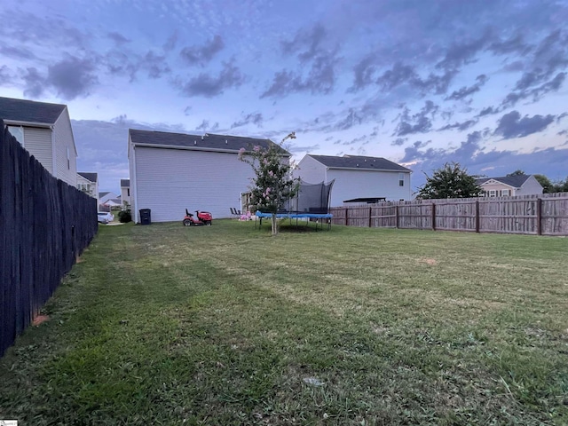 yard at dusk featuring a trampoline