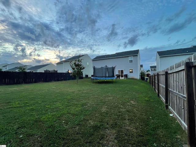 yard at dusk featuring a trampoline