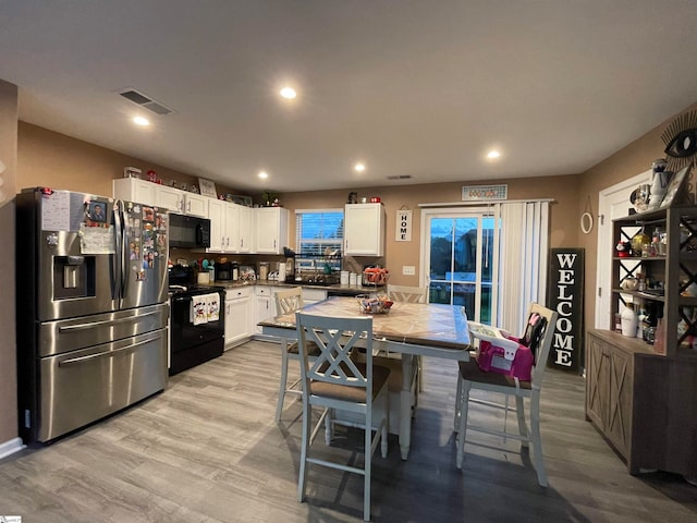 kitchen featuring white cabinets, light hardwood / wood-style floors, and black appliances