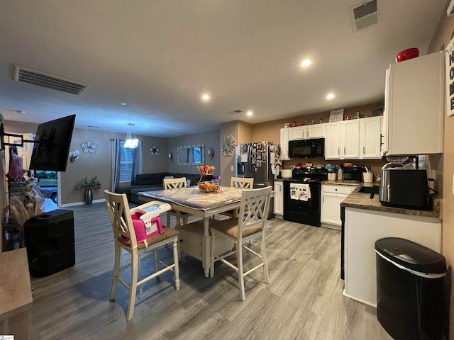 kitchen featuring light wood-type flooring, white cabinetry, and black appliances