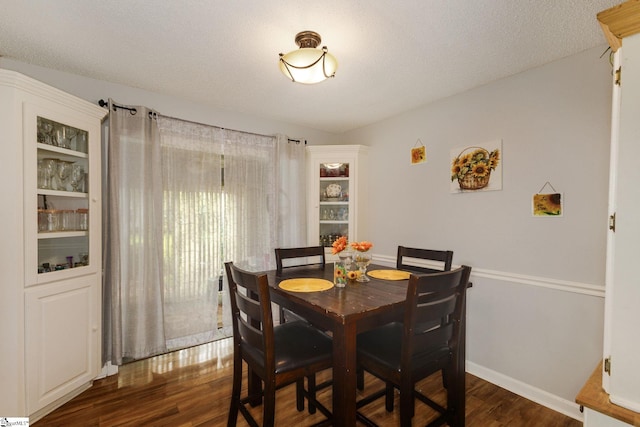 dining space with a textured ceiling and dark hardwood / wood-style floors