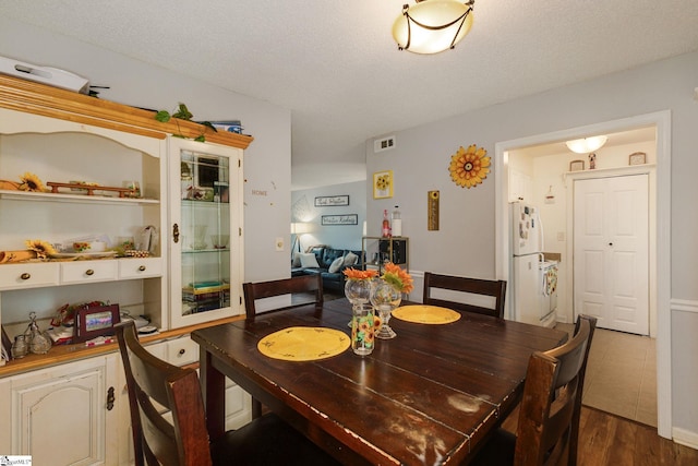 dining space featuring a textured ceiling and dark hardwood / wood-style floors