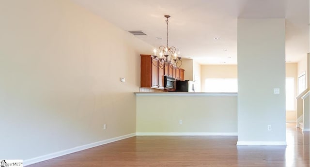 empty room featuring a chandelier, plenty of natural light, and wood-type flooring