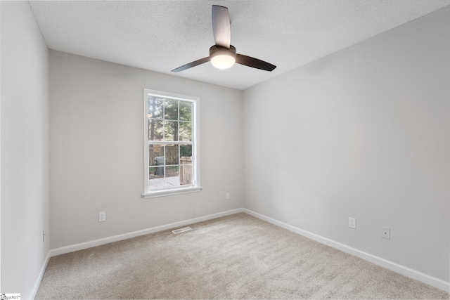 empty room with light carpet, a textured ceiling, and ceiling fan