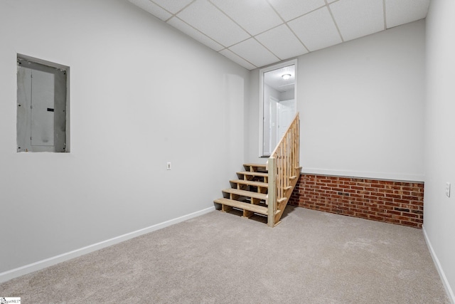 basement with carpet flooring, electric panel, and a paneled ceiling