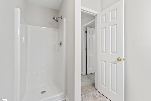 bathroom featuring tile patterned floors, a shower, and a textured ceiling