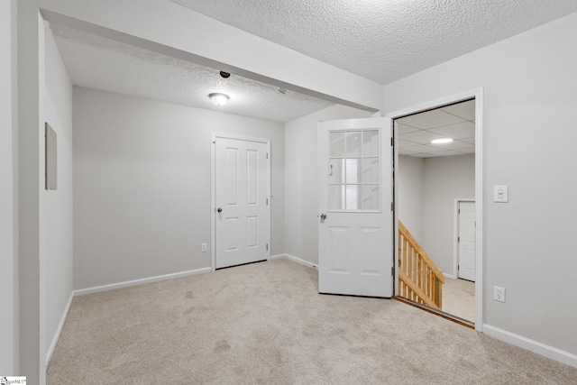 carpeted spare room featuring beam ceiling and a textured ceiling