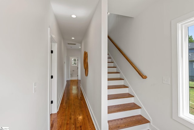 stairway featuring a healthy amount of sunlight and hardwood / wood-style flooring