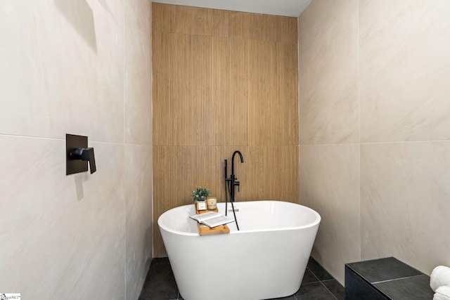 bathroom with tile patterned flooring, tile walls, and a bathtub